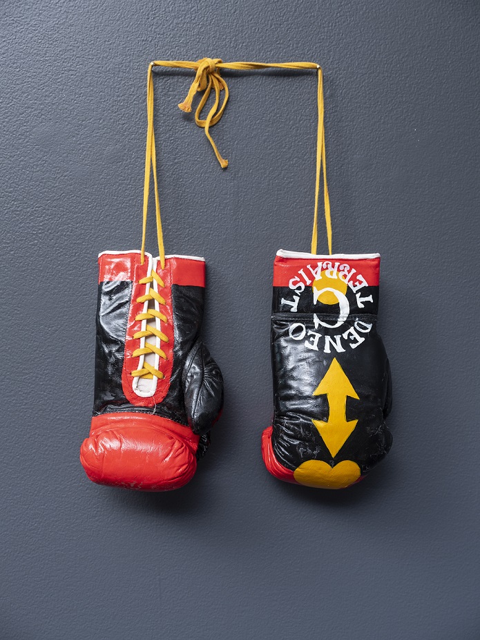 Gordon Hookey, Terraist gloves, 2008, mixed media. Installation view, OCCURRENT AFFAIR, UQ Art Museum, 2021. Collection of The University of Queensland, purchased 2008. Reproduced courtesy of the artist and Milani Gallery, Brisbane. Photo: Carl Warner