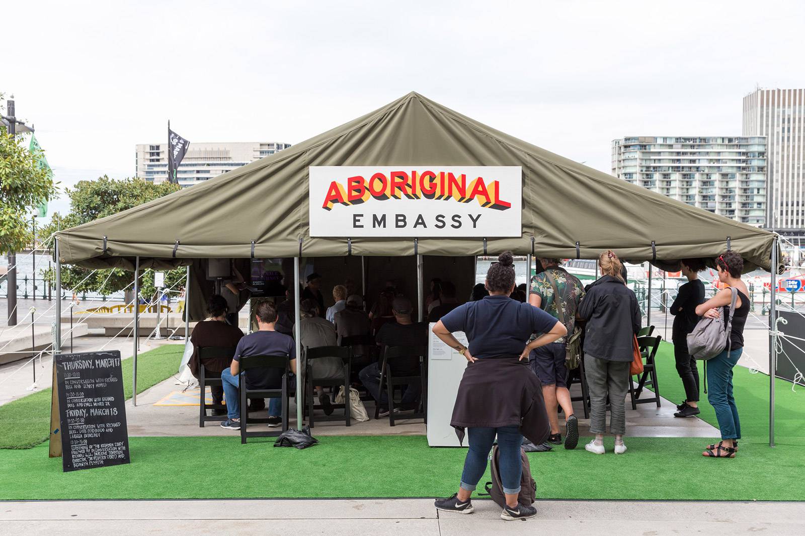 Richard Bell, Embassy 2013, canvas tent with annex, alumninium frame, rope, synthetic polymer paint on ply; 16mm film transferred to single-channel digital video, black and white, sound; archive. Museum of Contemporary Art Australia and Tate, with support from the Qantas Foundation in 2015, purchased 2017