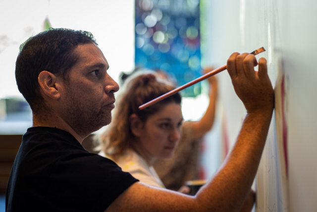 Tony Albert with University students, Terra Nullius (with Scrooge) (in progress), 2021, acrylic paint on plaster wall. Installation view, OCCURRENT AFFAIR, UQ Art Museum, 2021. Reproduced courtesy of the artist and Sullivan + Strumpf, Sydney. Photo: Simon Woods