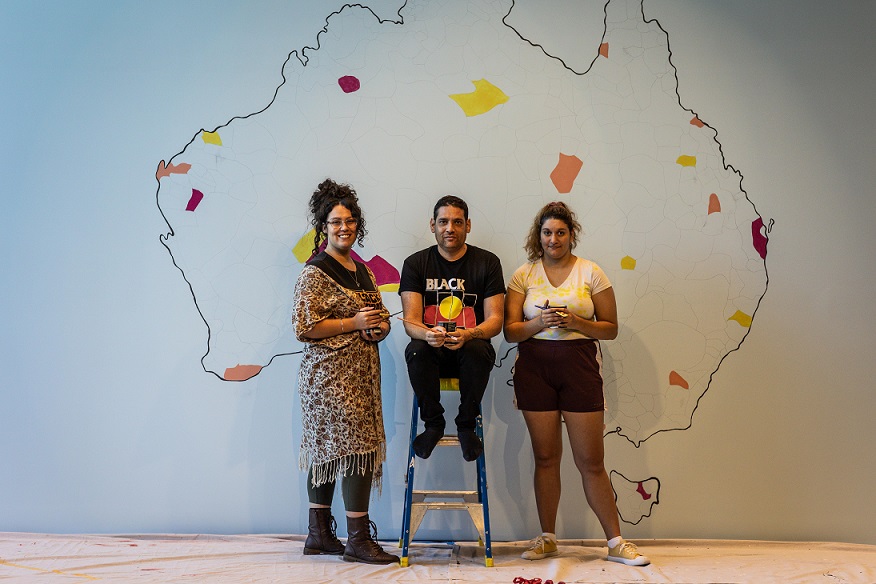 Tony Albert with University students, Terra Nullius (with Scrooge) (in progress), 2021, acrylic paint on plaster wall. Installation view, OCCURRENT AFFAIR, UQ Art Museum, 2021. Reproduced courtesy of the artist and Sullivan + Strumpf, Sydney. Photo: Simon Woods